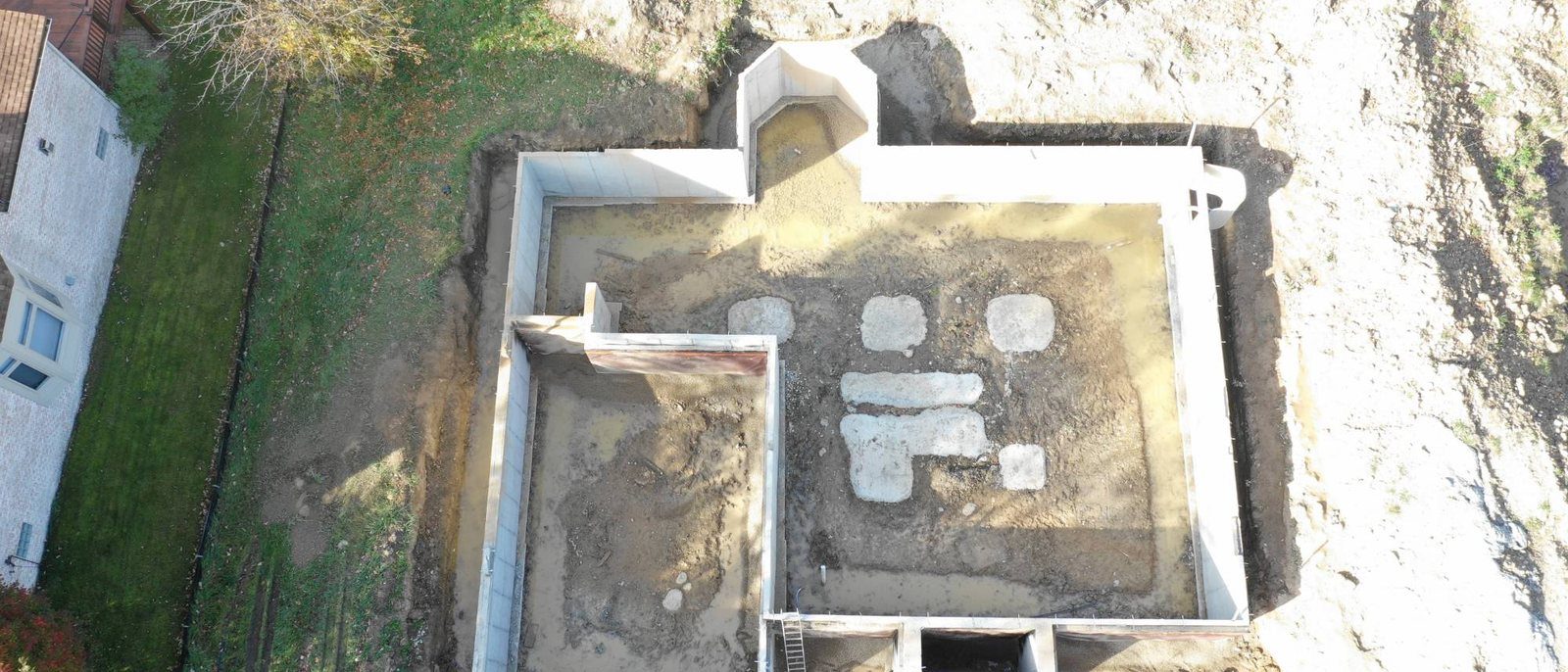 Aerial view of a new home foundation with poured walls before framing